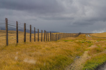 The boundary of a wooden fence with barbed wire and clouds