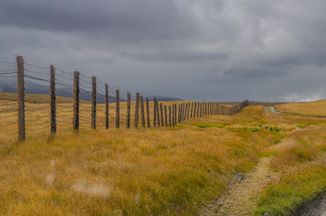 Obraz premium The boundary of a wooden fence with barbed wire and clouds