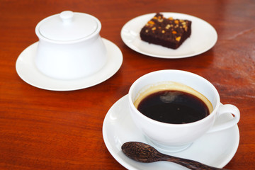 Close up of a cup of hot black coffee on a wooden table.