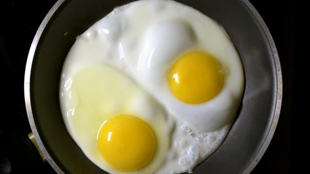 Two eggs fried in a pan. Time lapse. Vertical filming.