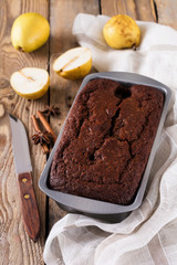 .Chocolate cake with pears and cinnamon on old wooden background. Selective focus.