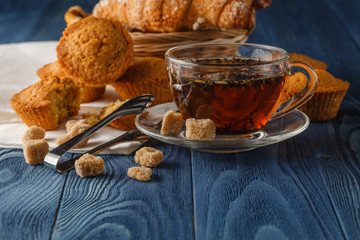 Ceylon black tea in glass cups, fresh croissants, vintage wooden