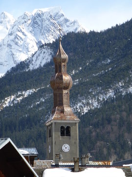 Church spire in the village of Bozel, French Alps, with snow-covered Mountain peak behind