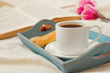 Romantic breakfast in the bed: cookies, hot coffee, flowers and