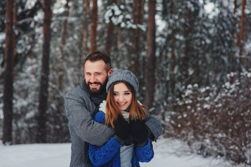 Fototapeta na wymiar happy loving couple walking in snowy winter forest, spending christmas vacation together. Outdoor seasonal activities. Lifestyle capture.