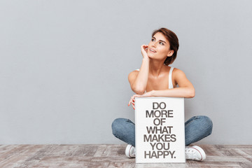 Smiling woman sitting on the floor with motivational board