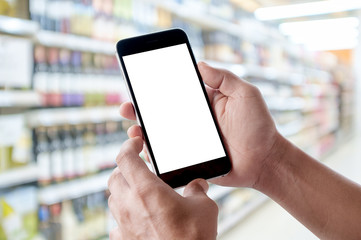Hand holding blank screen of smartphone device in supermarket.
