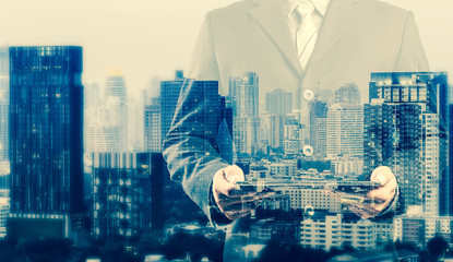 Double exposure of success businessman using digital tablet with city landscape background