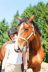 Obraz premium Young teenage girl equestrian standing with her brown horse