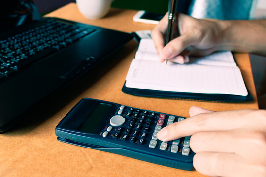 Young business woman writing make note report and counting calcu