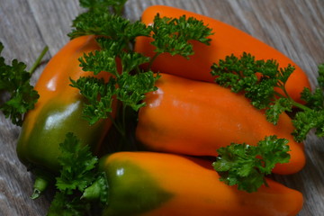 Obraz na płótnie Canvas beautiful bright orange and green sweet bell pepper and a sprig of green parsley on a wooden background, food, cooking