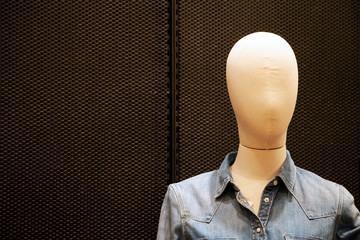 Faceless female mannequin wearing cheap casual jean jacket at shopping mall