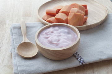 Ripe papaya slices on wooden dish and yogurt for healthy breakfa