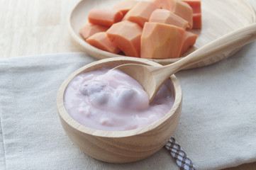 Ripe papaya slices on wooden dish and yogurt for healthy breakfa