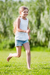 Glad girl in elementary school age running on grass
