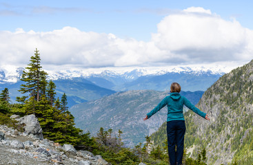 Happy hiker with outstretched arms looking at amazing view and feeling freedom happiness, achievement in mountains. Concept of lifestyle without stress. Wedgemount trail British Columbia