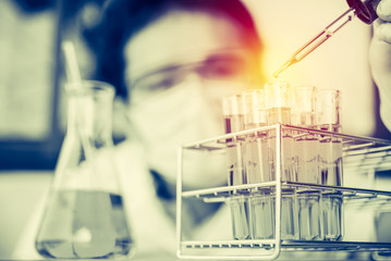 Glass laboratory chemical test tubes with liquid.Man wears prote