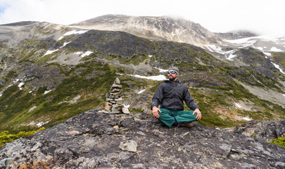 Traveler man relaxing meditation near cairn and enjoying mountains view landscape. Travel Lifestyle hiking concept summer vacations outdoor. Wedge mount hiking trail British Columbia Canada