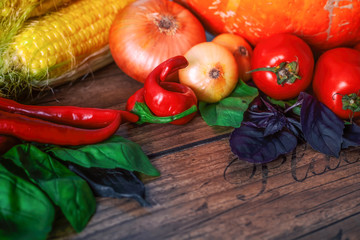 Fresh vegetables on a dark table. Autumn background. Healthy eating. Pumpkin, bell peppers, paprika, tomatoes,basil, onion, corn cob. Top view. Closeup, selective focus.