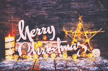 Merry Christmas Background, Fairy Lights,Wood craft rustic Xmas background with wooden letters.Ornaments.Gifts in Boxes, Candle light.Bright lights garlands