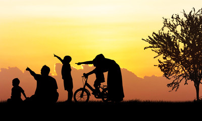 Fototapeta premium Silhouette of Happy family playing in field sunset background