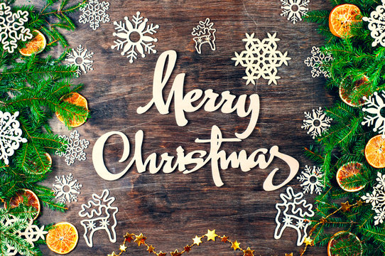 Merry Christmas backgrounds.Spruce branches, snowflakes, deer, dried oranges.Christmas decorations.A garland of gold stars.Lettering.
