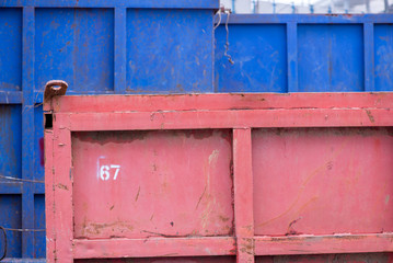 A background of red and blue sand tipper containers at a construction site. Construction and transport concept.