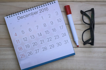 Travel planning - black pen on calendar and glasses on wooden background.
