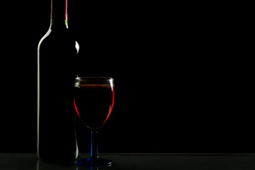 Glass and bottle of wine isolated on a black background