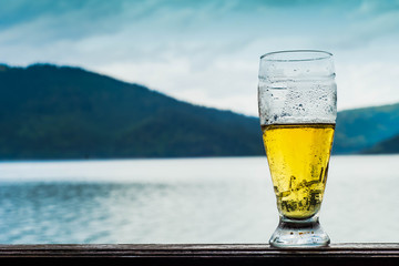 Glass of beer on a mountain lake