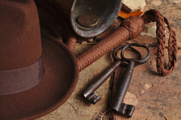 Fedora hat, bullwhip and relics on an antique tiled floor. Indiana theme - obrazy, fototapety, plakaty
