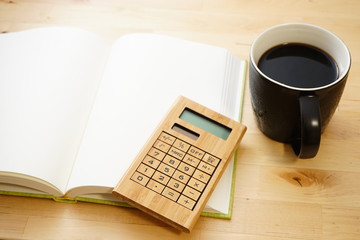 Cup of coffee with notebook and pens on wooden desk