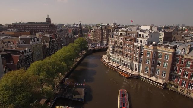 Aerial. Tour boats on water channel in Amsterdam. Camera moves forward. 4K
