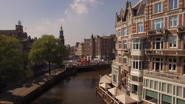 Aerial. Tour boats on water channel in Amsterdam. Camera moving up. 4K