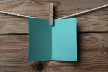 Turquoise Blue Greetings Card Pegged to String on Wood Backgroun