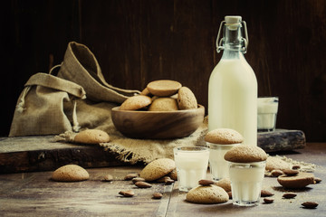 Cow's milk in the bottle and a glass and cookies with almond ama