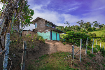 farmhouse with teal walls underneath the blue sky of the midday sun