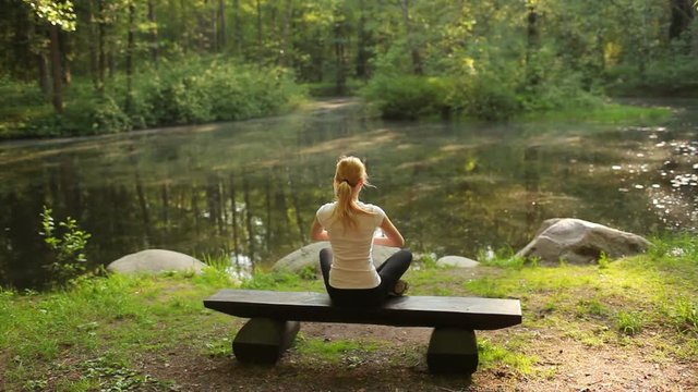 Woman Doing Yoga Sitting on a Bench in the Woods