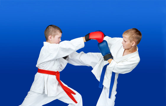 Boys with red and blue belts are hitting blows arm and leg