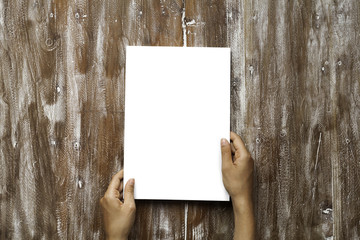 Closeup Blank White Paper Sheet Mockup Holding Male Hands Natural Wood Table Background. Empty Canvas Painted Brown Desk.