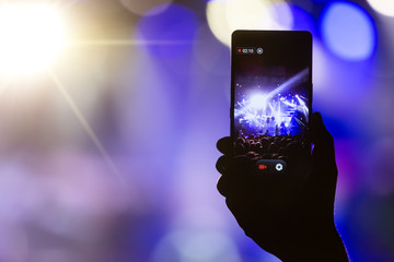 People taking photographs with touch smart phone during a music