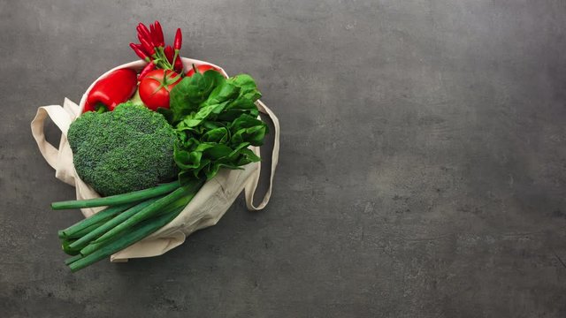 Top view on shopping bag full of vegetables with cooking accessories laying on kitchen table. 4K, stopmotion animation.