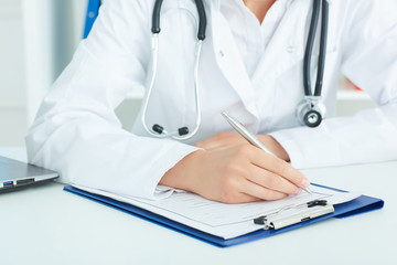 Female medicine doctors hands filling patient medical form. ealth care, insurance and help concept.