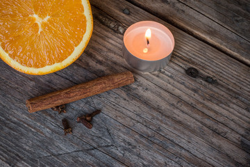 Weihnachtshintergrund: Orange, Zimt, Nelken und Teelicht auf Holzuntergrund