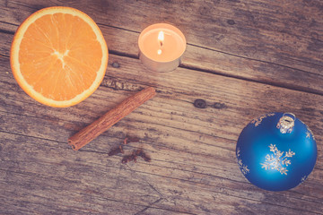 Weihnachtshintergrund: Orange, Zimt, Nelken, Teelicht und Christbaumkugel auf Holzuntergrund, retro