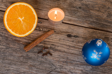 Weihnachtshintergrund: Orange, Zimt, Nelken, Teelicht und Christbaumkugel auf Holzuntergrund