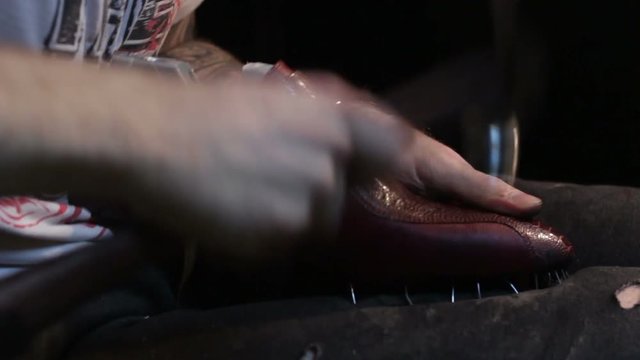 Shoemaker sews shoes, hammering sole