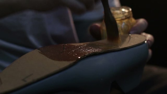 Shoemaker sews shoes, hammering sole