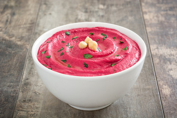 Beet hummus in a bowl on wooden table

