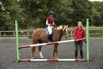 Erecting a jump in an outdoor riding school - September 2016 - Riding instructor lifting a pole to...